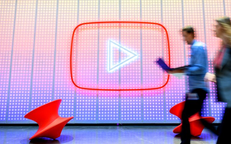 Un grupo de personas camina junto a un logotipo de YouTube, mientras Google celebra el 20 aniversario del primer video subido a YouTube. 