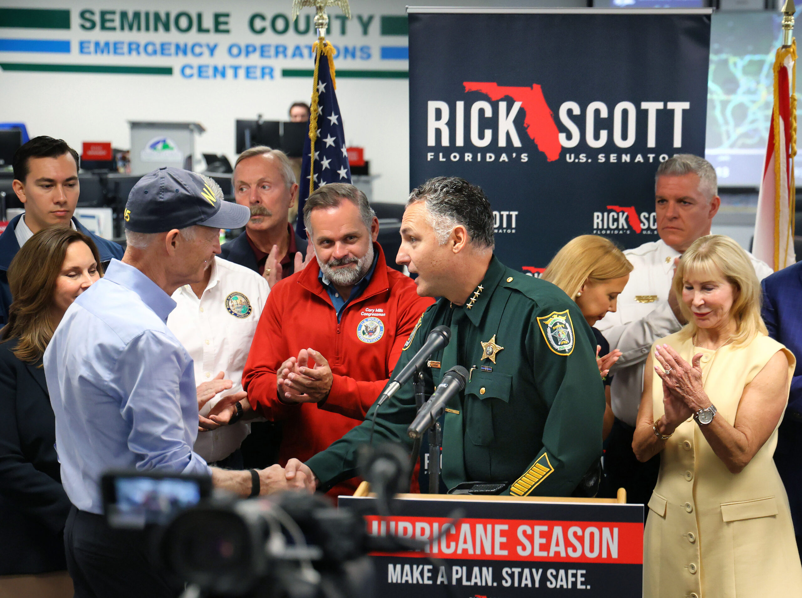 El sheriff del condado de Seminole, Dennis Lemma, agradece al senador Rick Scott, a la izquierda, con el congresista Cory Mills, Centro, durante su visita al Centro de Operaciones de Emergencia del Condado de Seminole para una conferencia de prensa de conciencia de huracanes, en Sanford el 29 de mayo. Scott se unió a los funcionarios locales elegidos y de respuesta de emergencia. (Joe Burbank/Orlando Sentinel)