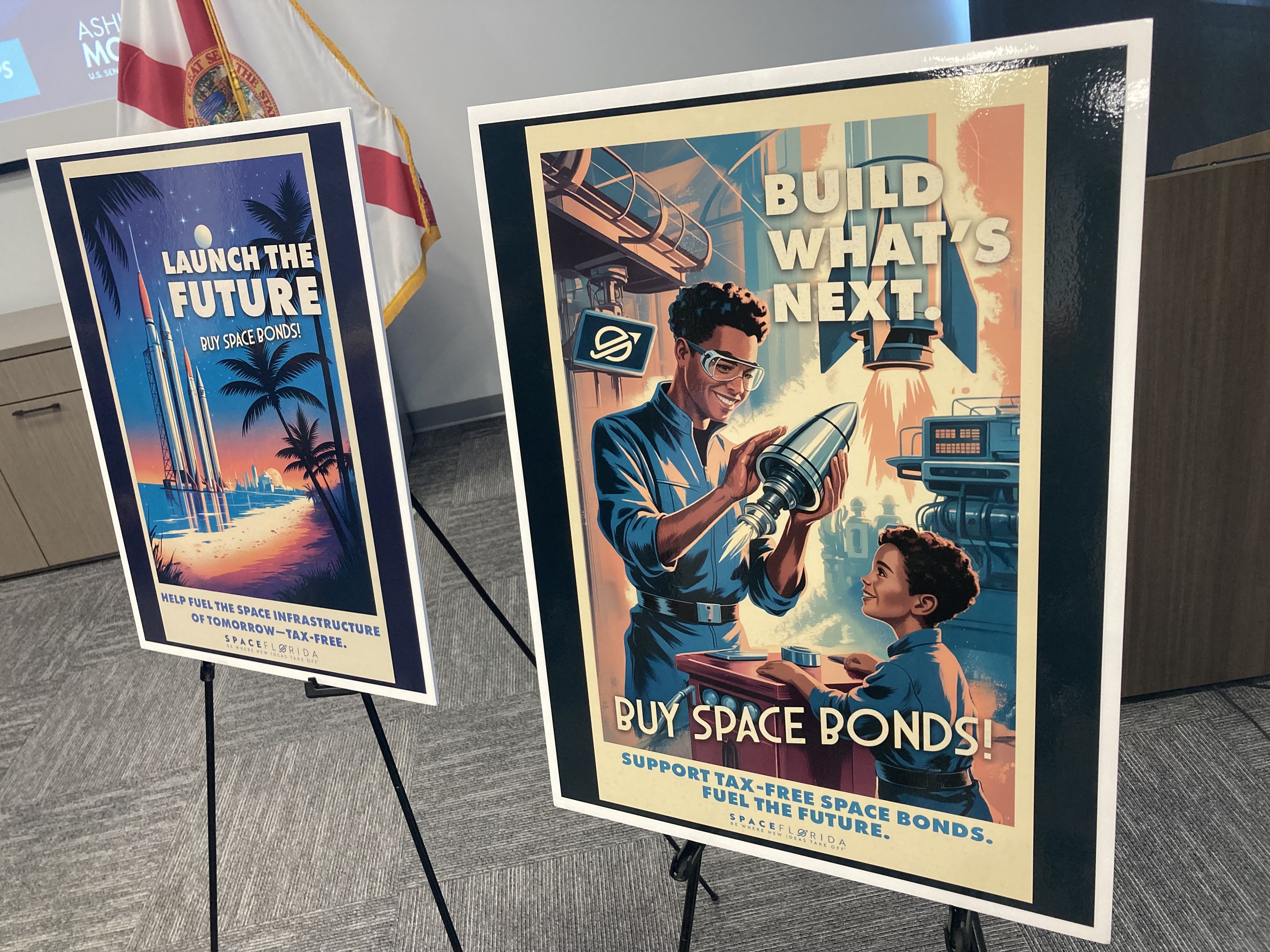 Los pancartas que promueven bonos espaciales acompañan una presentación en Space Florida sobre bonos libres de impuestos para motos espaciales. (Richard Tribou/Orlando Sentinel)