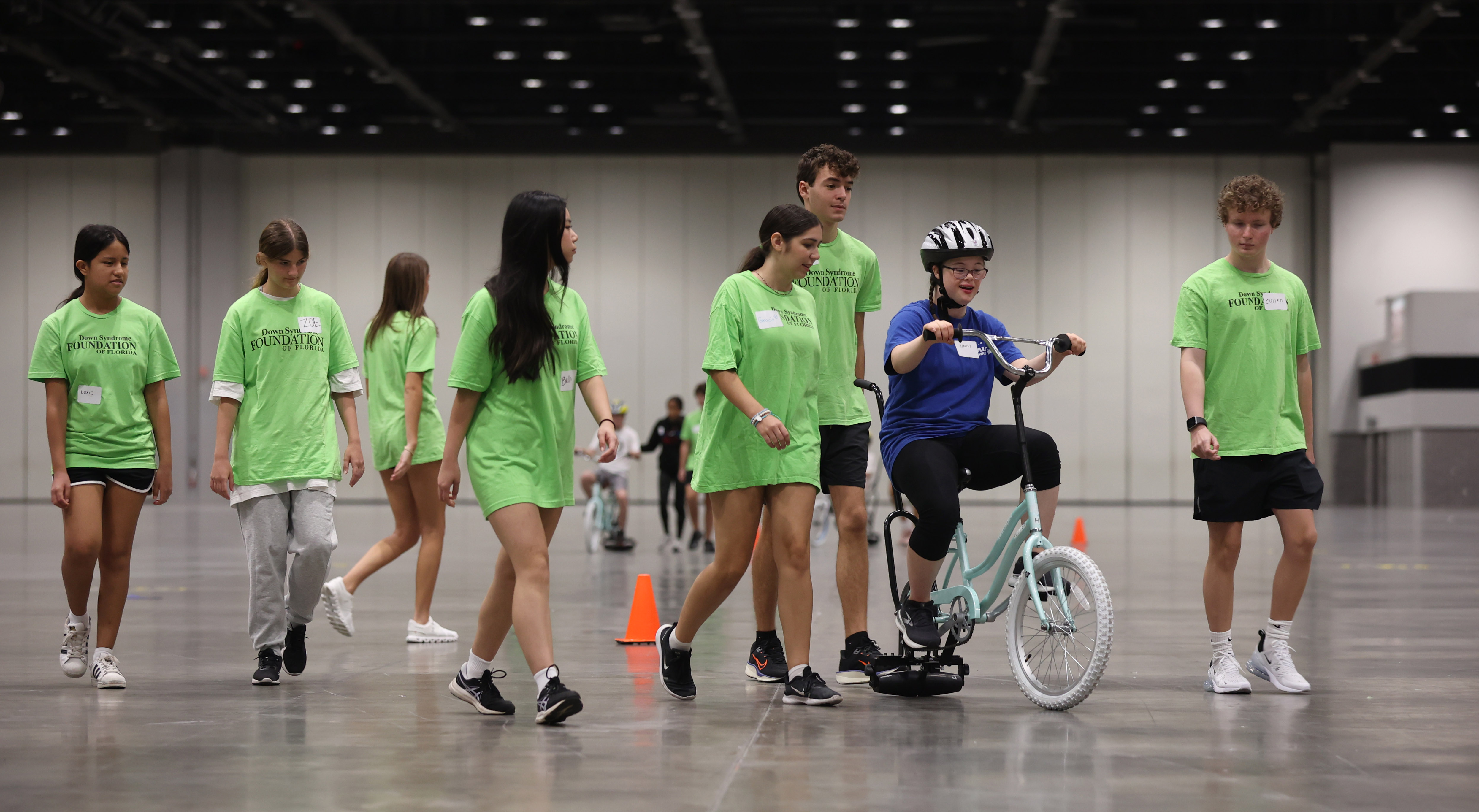 ¡Hailey Dean, de 15 años, monta una bicicleta de rodillo acompañada de voluntarios La Fundación del Síndrome de Down de Florida organiza un ICAN! Campamento de bicicletas en el Centro de Convenciones del Condado de Orange, el martes 22 de julio de 2025. (Ricardo Ramirez Buxeda/Orlando Sentinel)