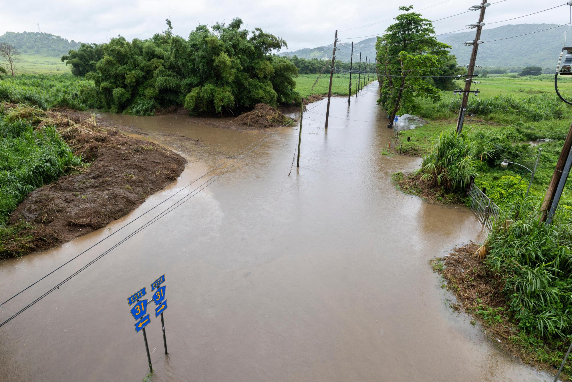El agua inunda un camino en Naguabo, Puerto Rico, cuando el huracán Erin trae lluvia a la isla, domingo 17 de agosto de 2025. (AP Photo/Alejandro Granadillo)