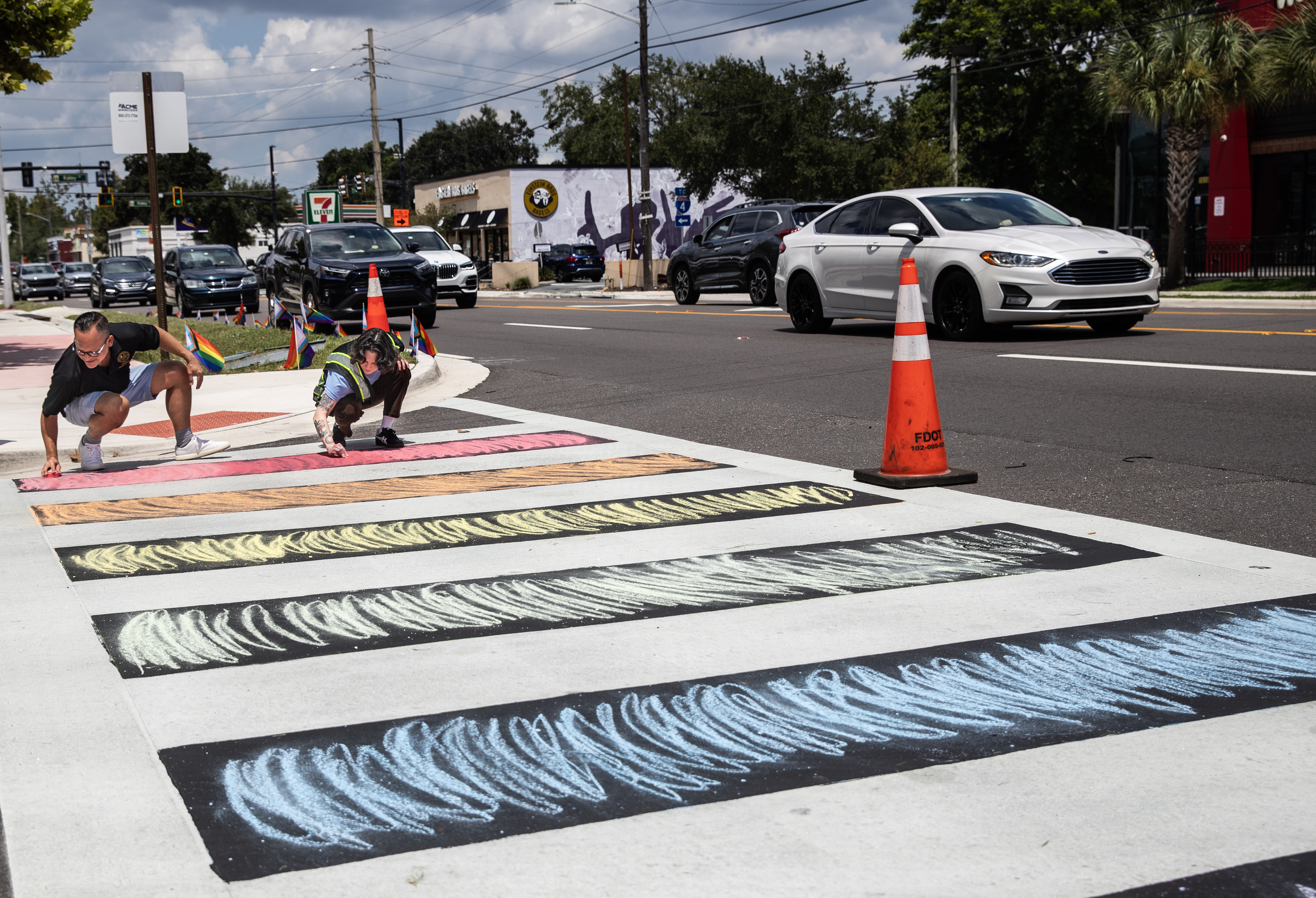 El senador Carlos Guillermo Smith ayuda a Dallas Perdew a colorear la acera con la tiza que trajo para devolver el color a la intersección en Orlando, Florida, el jueves 21 de agosto de 2025. 