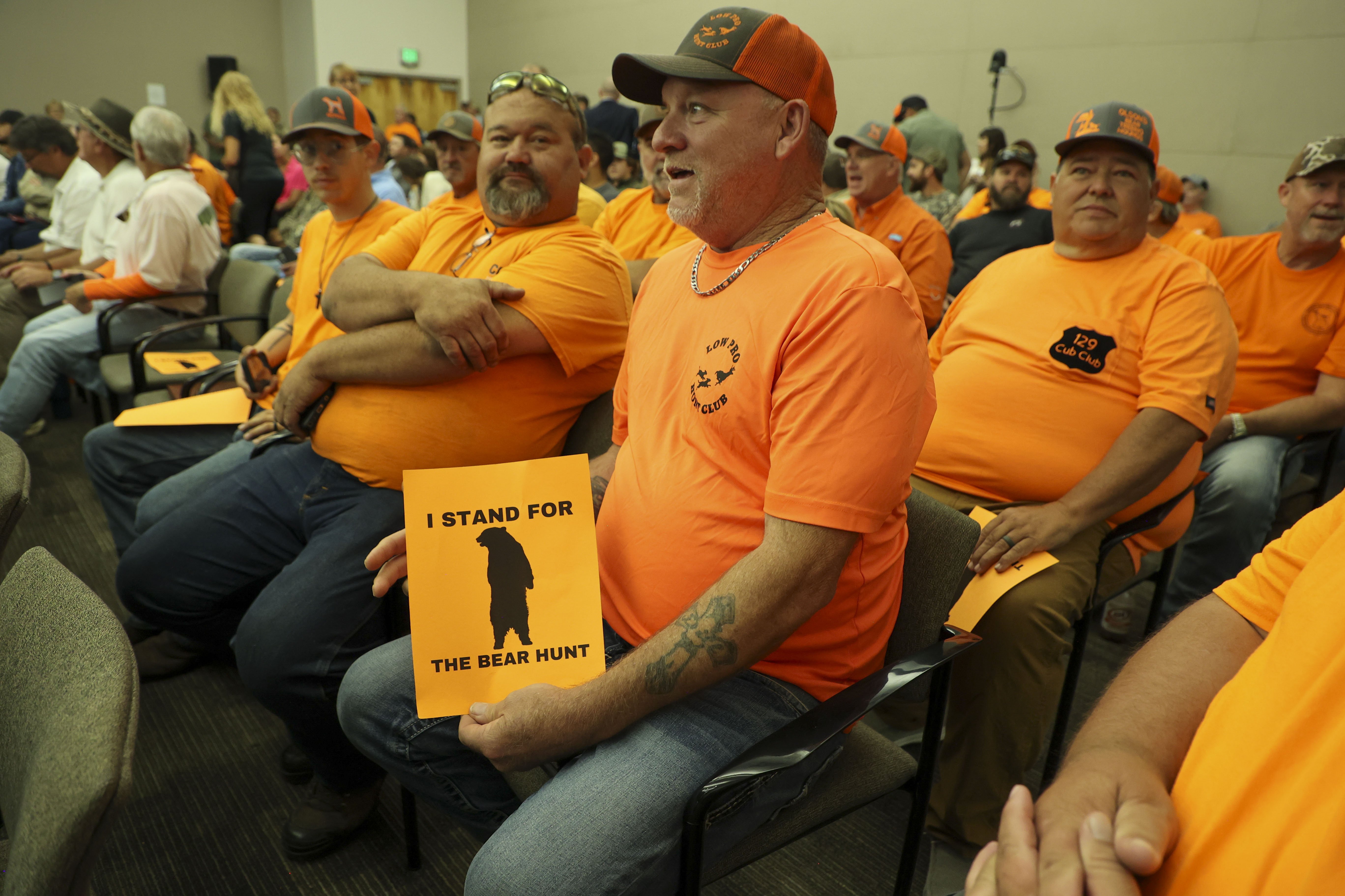 Donald Register, de Lake City, posee un signo en apoyo de una caza de osos mientras asiste a una reunión pública de la Comisión de Conservación de Pesca y Vida Silvestre de Florida el 21 de mayo en el Colegio de Florida Central en Ocala, donde los comisionados presentaron y discutieron las reglas propuestas para restablecer una búsqueda de oso negro de entrada limitada, la primera desde 2015.