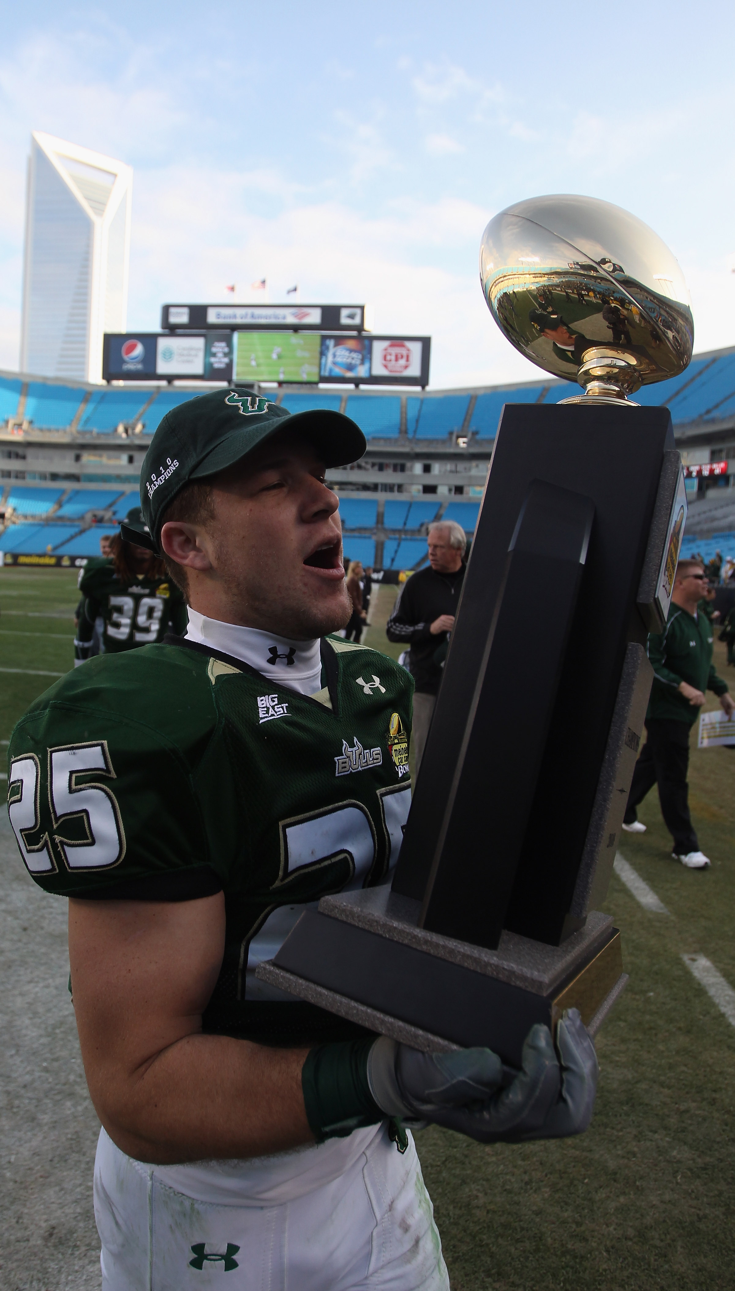 Joel Miller #25 de los Bulls de la USF sale del campo con el trofeo después de una victoria 31-26 sobre los Clemson Tigers durante su juego en el estadio Bank of America el 31 de diciembre de 2010 en Charlotte, Carolina del Norte. (Foto de Streeter Lecka/Getty Images)