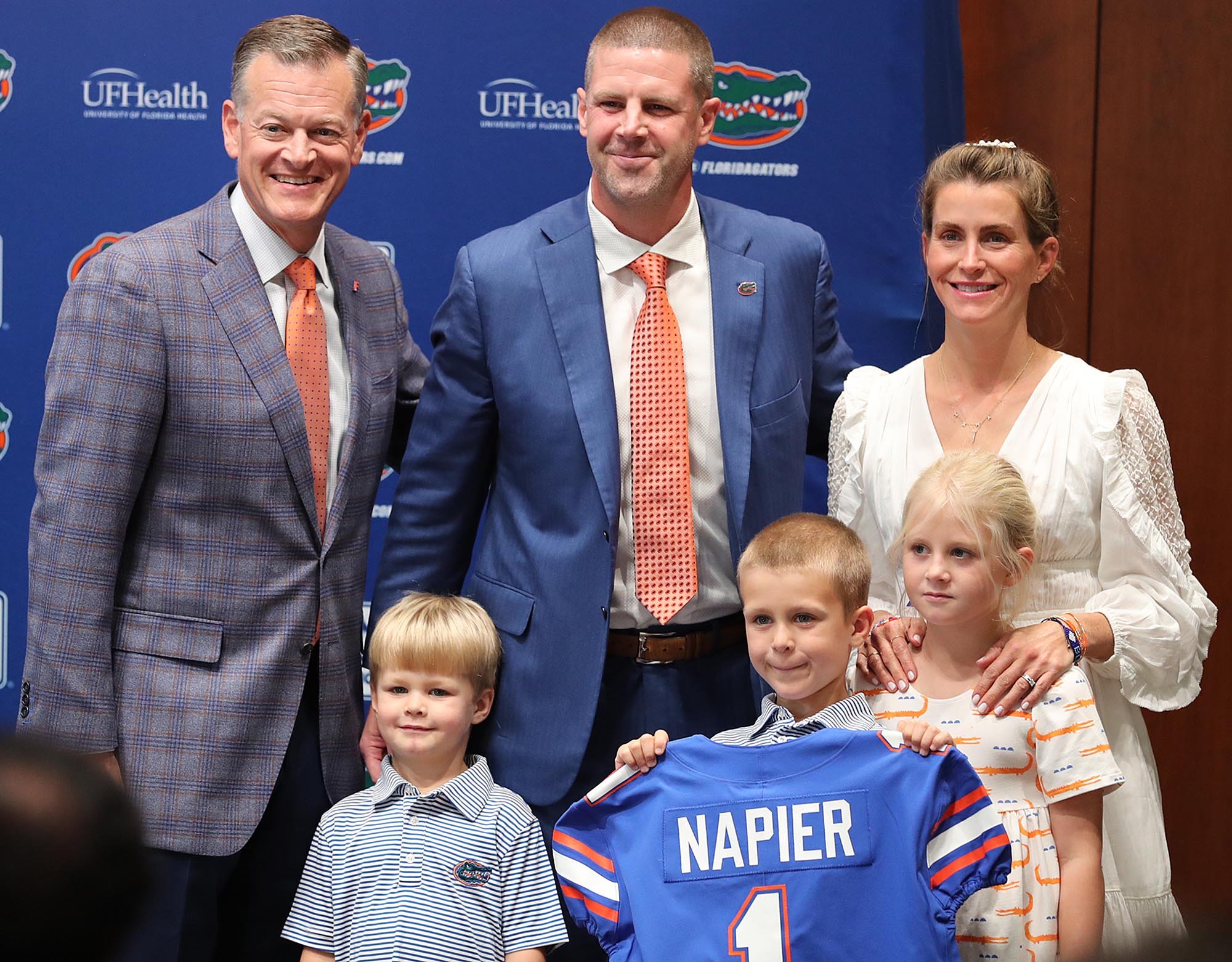 El director atlético de la UF, Scott Stricklin, arriba a la izquierda, posa con Billy Napier, en el medio superior, y su familia durante una conferencia de prensa en el estadio Ben Hill Griffin en el campus de la Universidad de Florida en Gainesville el 5 de diciembre de 2021. Napier fue presentado como el nuevo entrenador en jefe del equipo de fútbol de la UF. La esposa de Napier, Ali, está en la esquina superior derecha. Los niños son, de izquierda a derecha: Charlie, Sammy Nelson y Annie. (Stephen M. Dowell/Orlando Sentinel)