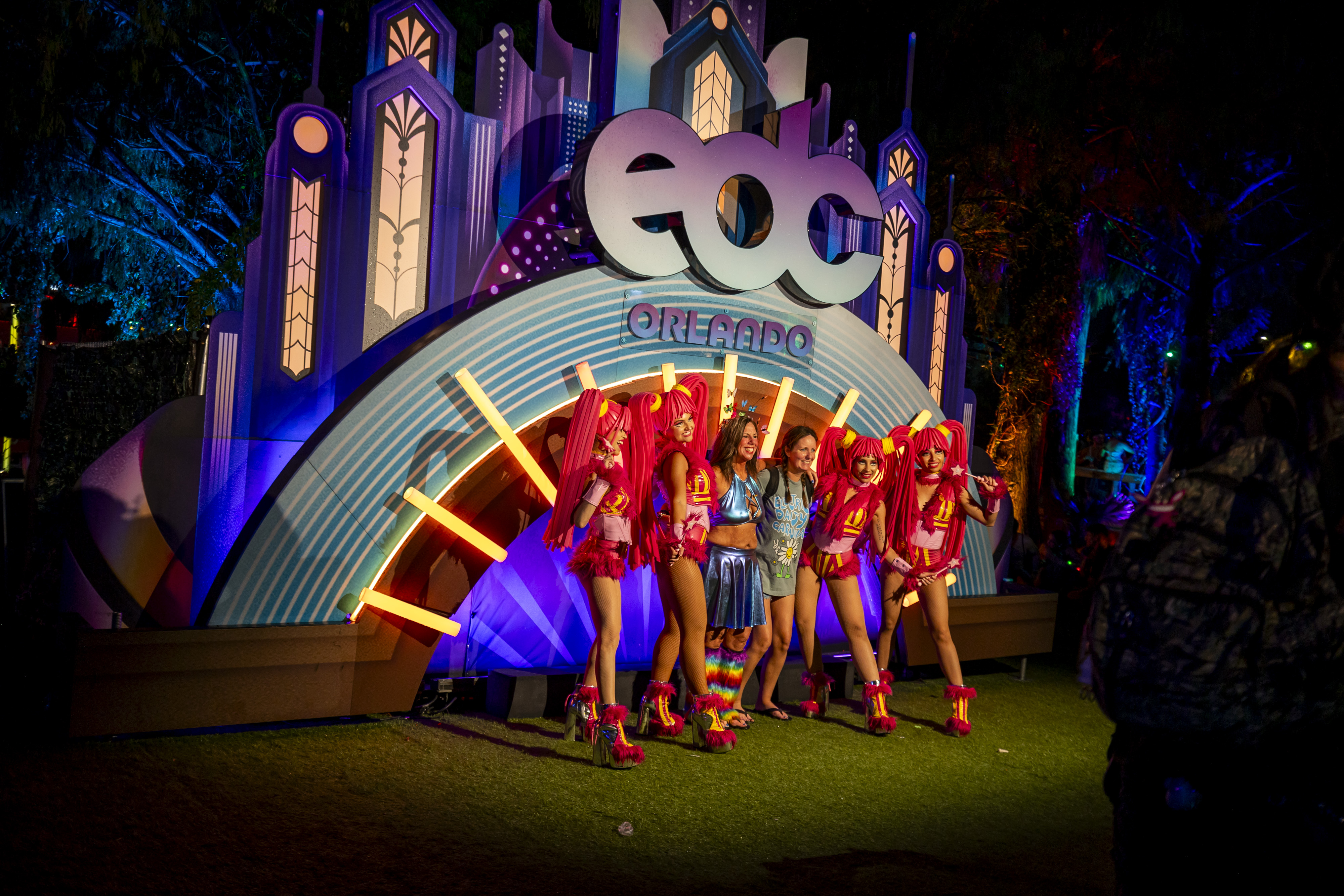 Los asistentes al festival se reúnen para tomarse una foto con artistas callejeros durante EDC Orlando en Tinker Field afuera del Camping World Stadium el 9 de noviembre de 2025. (Patrick Connolly/Orlando Sentinel)