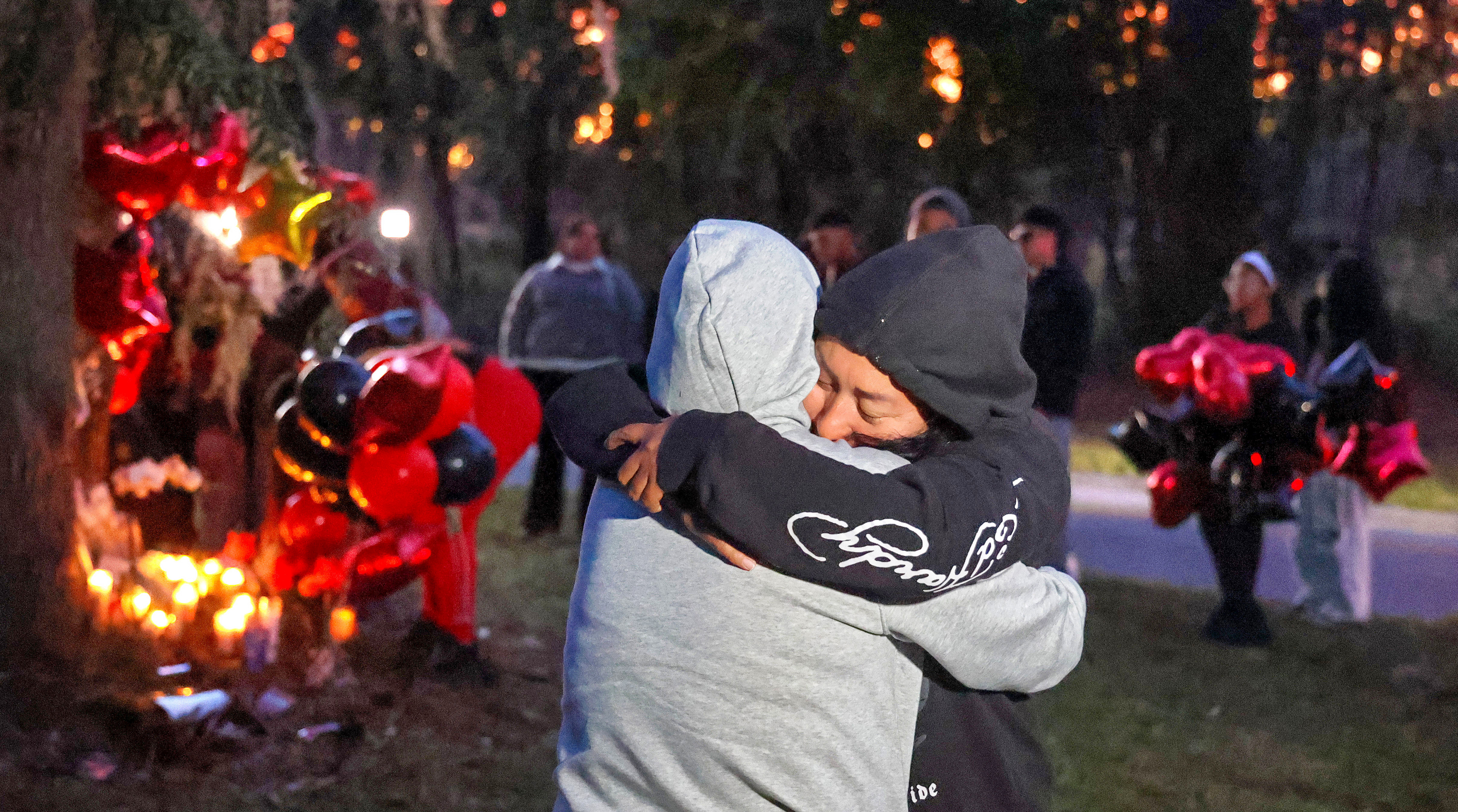Familiares y amigos de Julio López, Enrique Rodríguez Sabas y Leyner Velásquez, los tres adolescentes que murieron en un accidente en Apopka el domingo, lloran durante una vigilia con velas, al fondo, en el lugar del accidente en Welch Road, el lunes 10 de noviembre de 2025 por la noche. Los estudiantes asistieron a la escuela secundaria Apopka y a la escuela Kelly Park. (Joe Burbank/Orlando Sentinel)