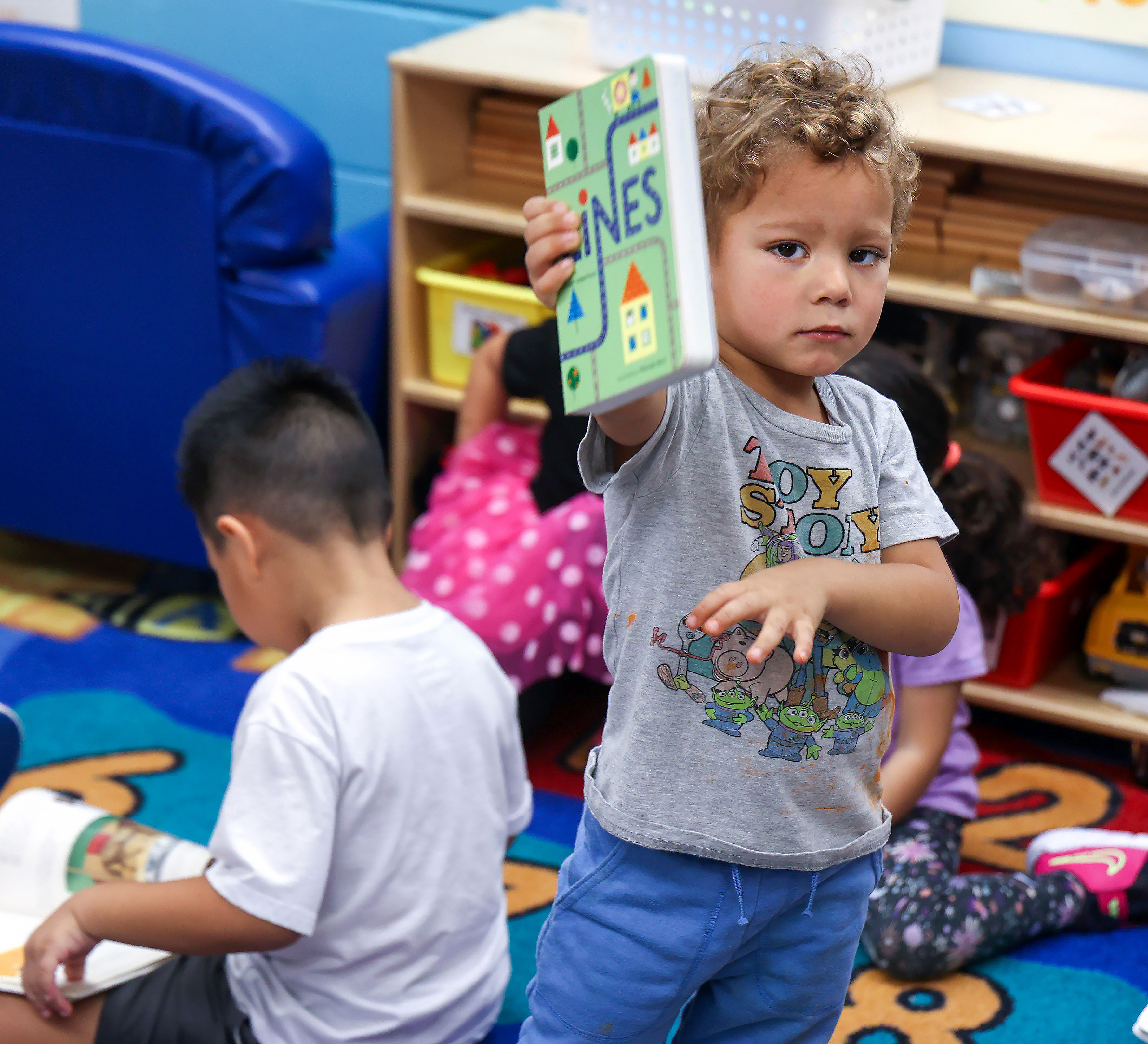 Sullivan Johnson ofrece su libro a un visitante en el aula VPK para niños de 3 años en Welbourne Nursery and Preschool en Winter Park, el martes 18 de noviembre de 2025. Las familias de bajos ingresos están encontrando más difícil el acceso a programas de aprendizaje temprano debido a los recientes recortes federales en el cuidado infantil subsidiado por el estado. (Joe Burbank/Orlando Sentinel)