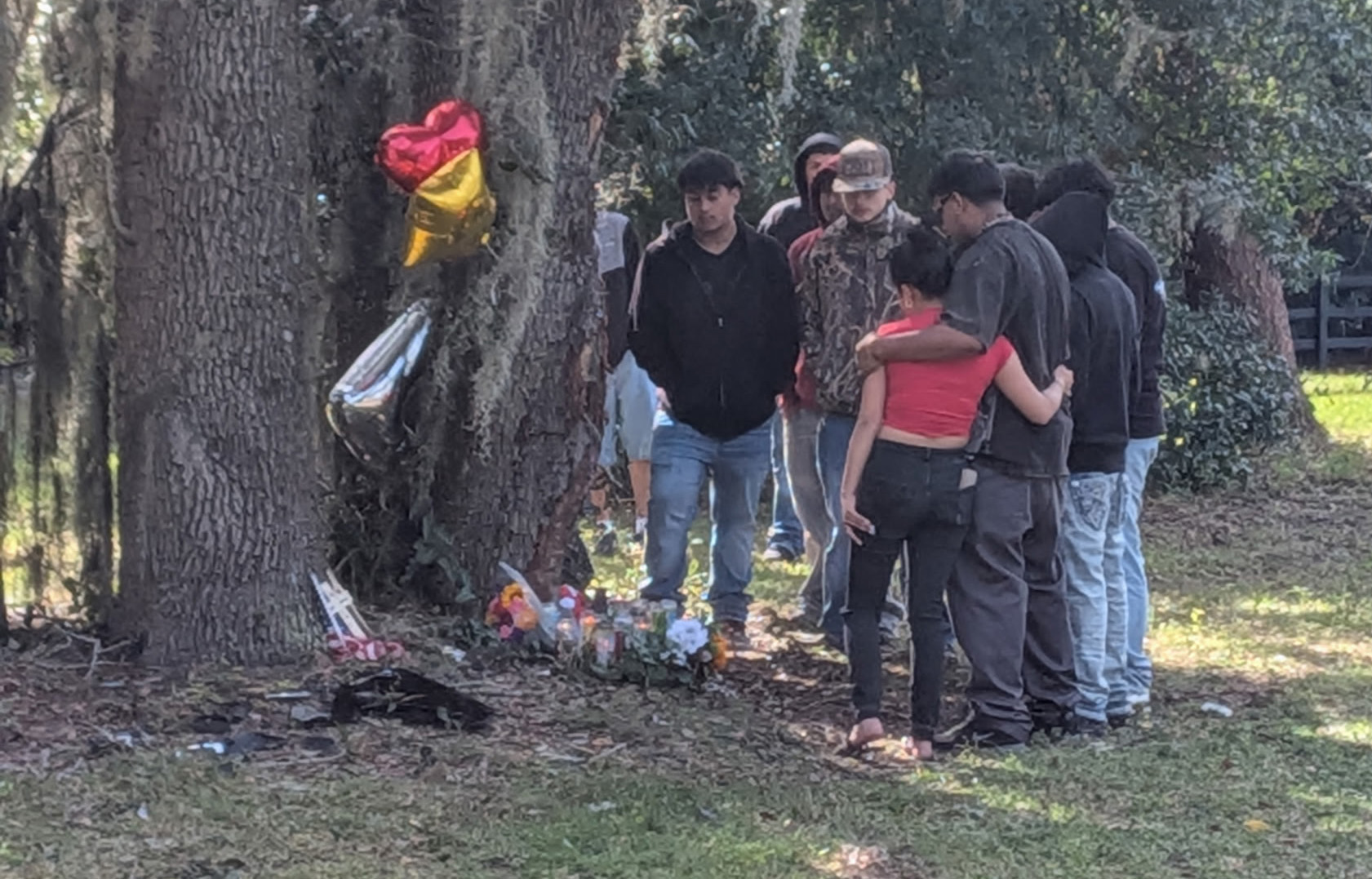 La gente se reúne el lunes 10 de noviembre de 2025 en Welch Drive y Wekiwa Drive en Apopka, el escenario de un accidente mortal que mató a tres adolescentes la madrugada del domingo 9 de noviembre de 2025. (Brian Bell/Orlando Sentinel)