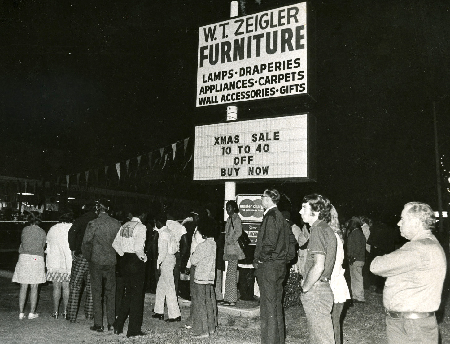 Los residentes del área se reúnen en la tienda de muebles WT Zeigler en 1975 después de que cuatro personas fueron encontradas muertas a tiros en Nochebuena. Dueño de la tienda, WT
