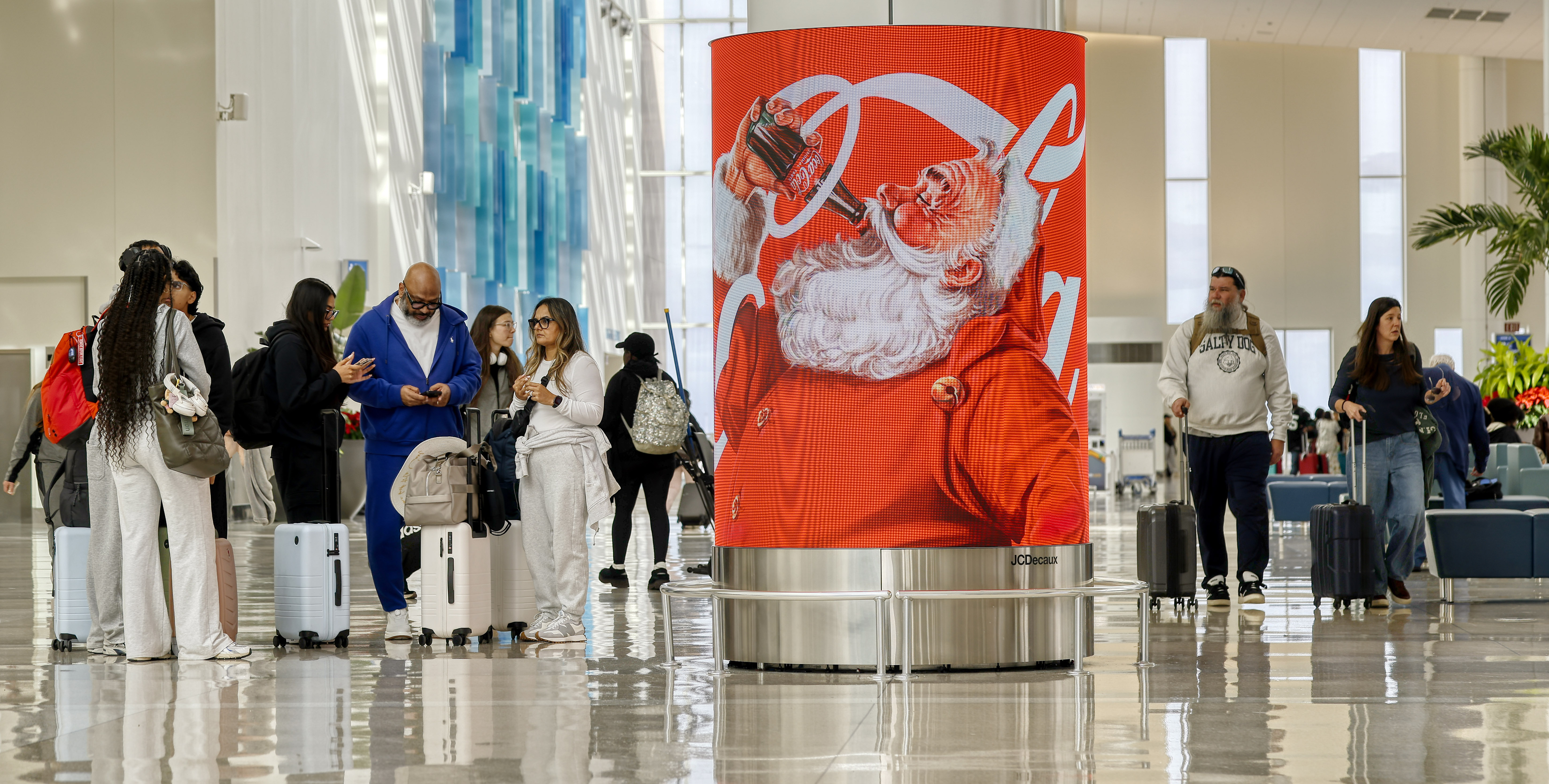 Papá Noel con un refresco en un anuncio navideño en la terminal C del Aeropuerto Internacional de Orlando, el miércoles 17 de diciembre de 2025. (Ricardo Ramirez Buxeda/Orlando Sentinel)