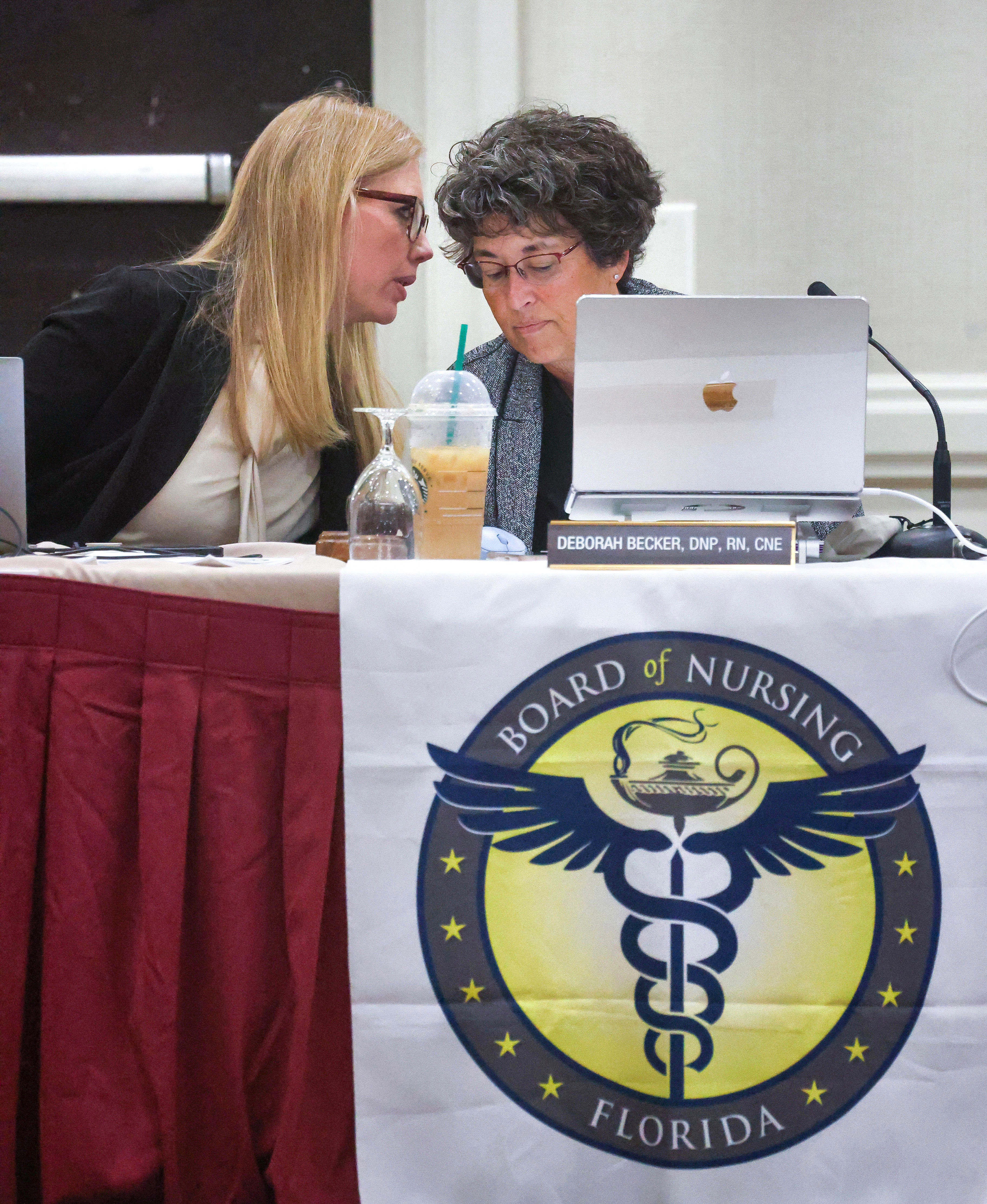 Jessica Nijem, Chief of Health Care Practitioner Regulation for the Florida Department of Health, left, confers with Florida Board of Nursing chair Dr. Deborah Becker during a meeting of the board in Maitland, Dec. 5, 2025. 