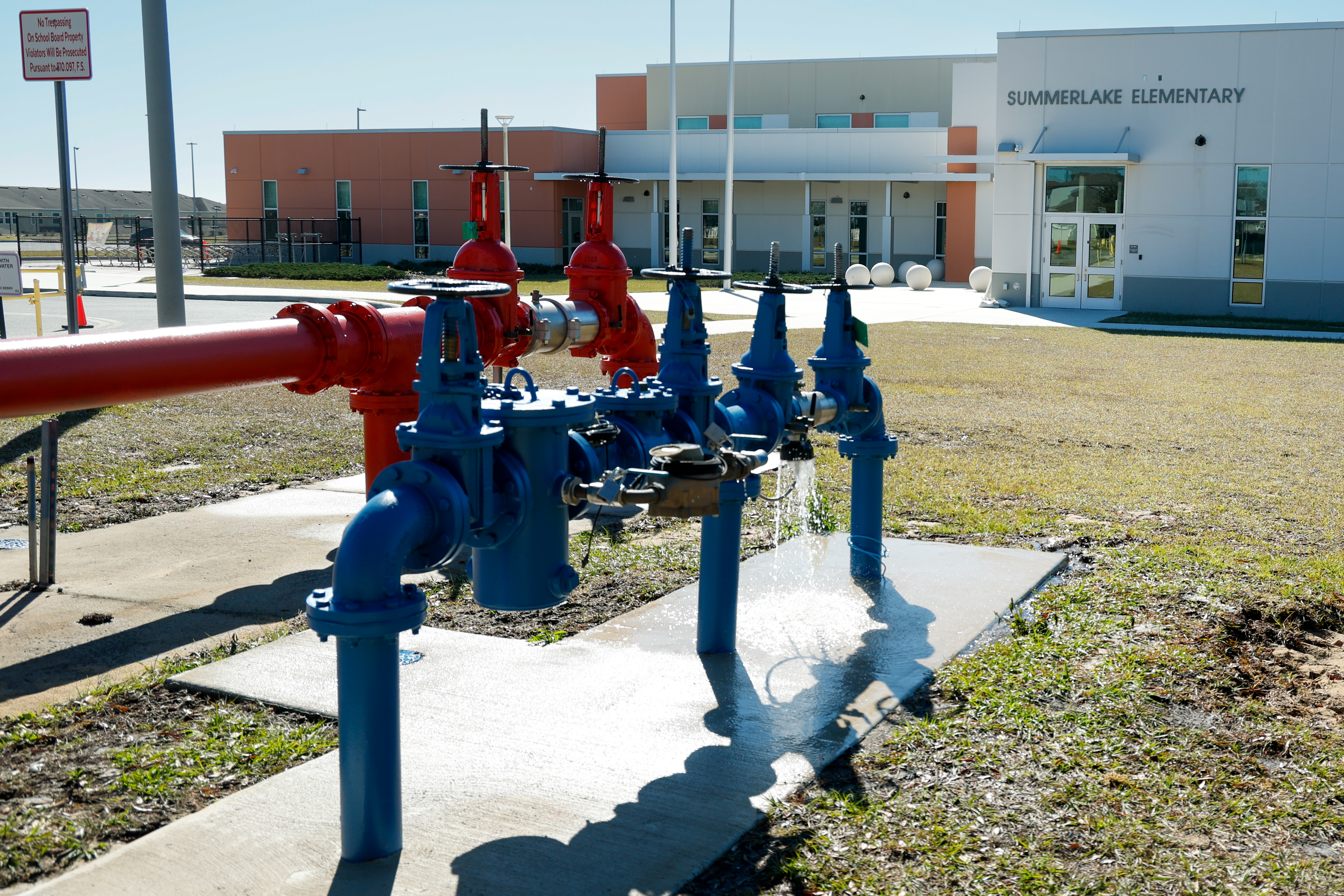 El agua sale de una gran válvula de agua frente a la escuela primaria Summerlake en Winter Garden el lunes 2 de febrero de 2026. La escuela cerró el lunes debido a problemas en las instalaciones debido al frío extremo. (Papa rico/Orlando Sentinel)