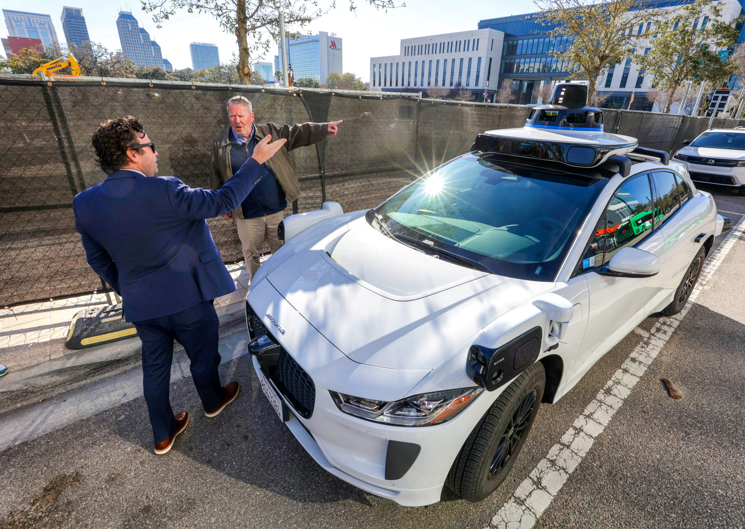 El gerente de políticas del sureste de Waymo, John Tupps, izquierda, explica las características del vehículo robotaxi totalmente autónomo al alcalde de Orlando, Buddy Dyer, en el primer día oficial de servicio en Orlando, el martes 24 de febrero de 2026. Orlando se unió a Dallas, Houston y San Antonio con el debut del servicio Waymo el martes, lo que eleva el total a 10 ciudades de EE. UU. que cuentan con el servicio de transporte sin conductor. (Joe Burbank/Orlando Sentinel)