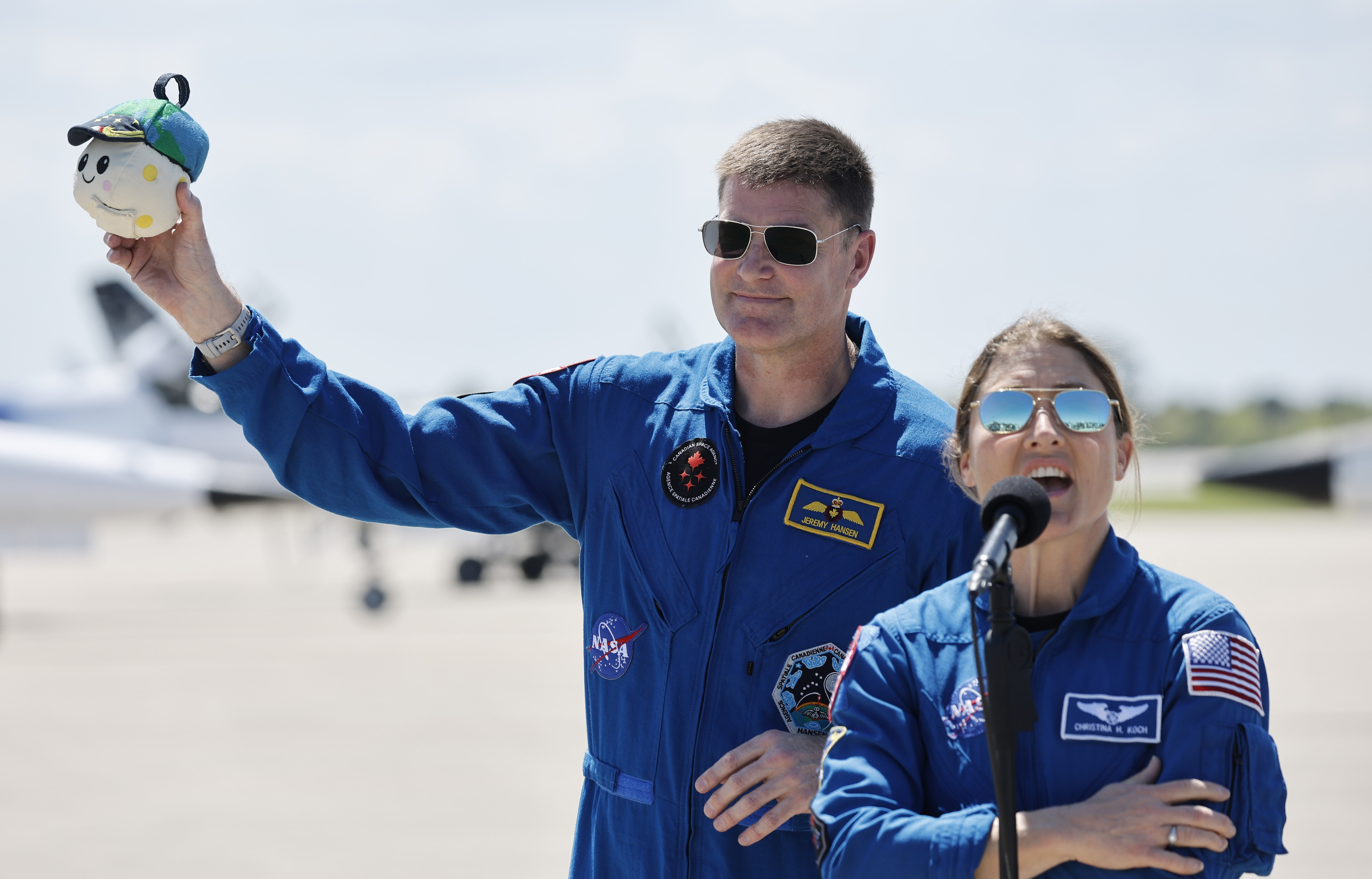 Jeremy Hansen, especialista en misión de Artemis, sostiene el indicador Zero-G, 'Rise' mientras la especialista en misión Christina Hammock Koch habla con los medios al llegar a la instalación de aterrizaje del Shuttle en Cabo Cañaveral, Florida, el viernes 27 de marzo de 2026. (Ricardo Ramirez Buxeda/Orlando Sentinel)