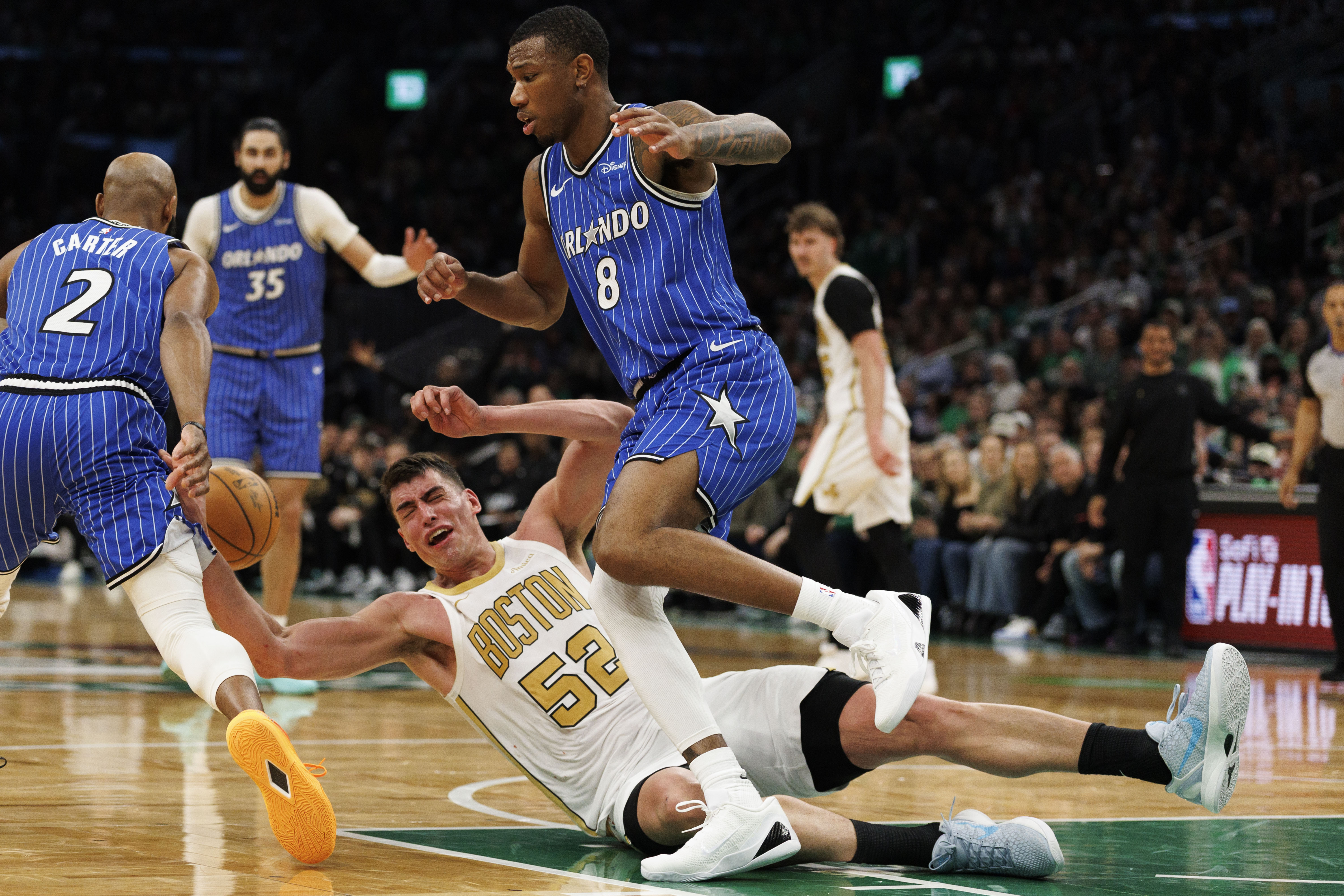 BOSTON, MASSACHUSETTS: El centro de los Boston Celtics, Luka Garza, es tropezado por el delantero del Orlando Magic, Jamal Cain, a la derecha, durante la segunda mitad contra el Orlando Magic en el TD Garden el 12 de abril de 2026. (CJ Gunther/Boston Herald)
