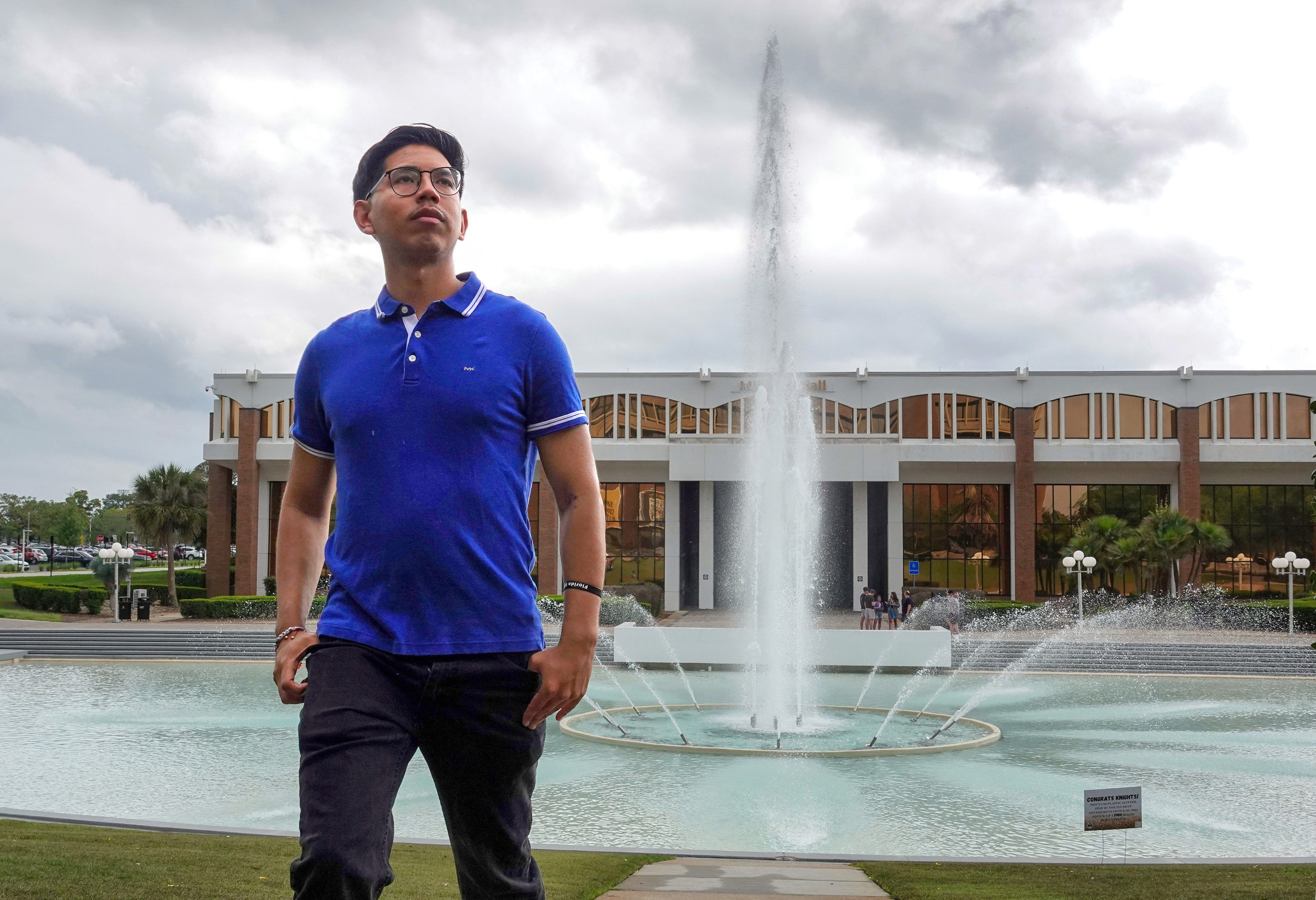 Alexander Vallejos, estudiante de último año de la UCF, camina frente al icónico estanque reflectante de la escuela, el lunes 6 de abril de 2026. Vallejos se encuentra entre los estudiantes de DACA que se han visto afectados por la represión migratoria de la administración Trump. (Joe Burbank/Orlando Sentinel)