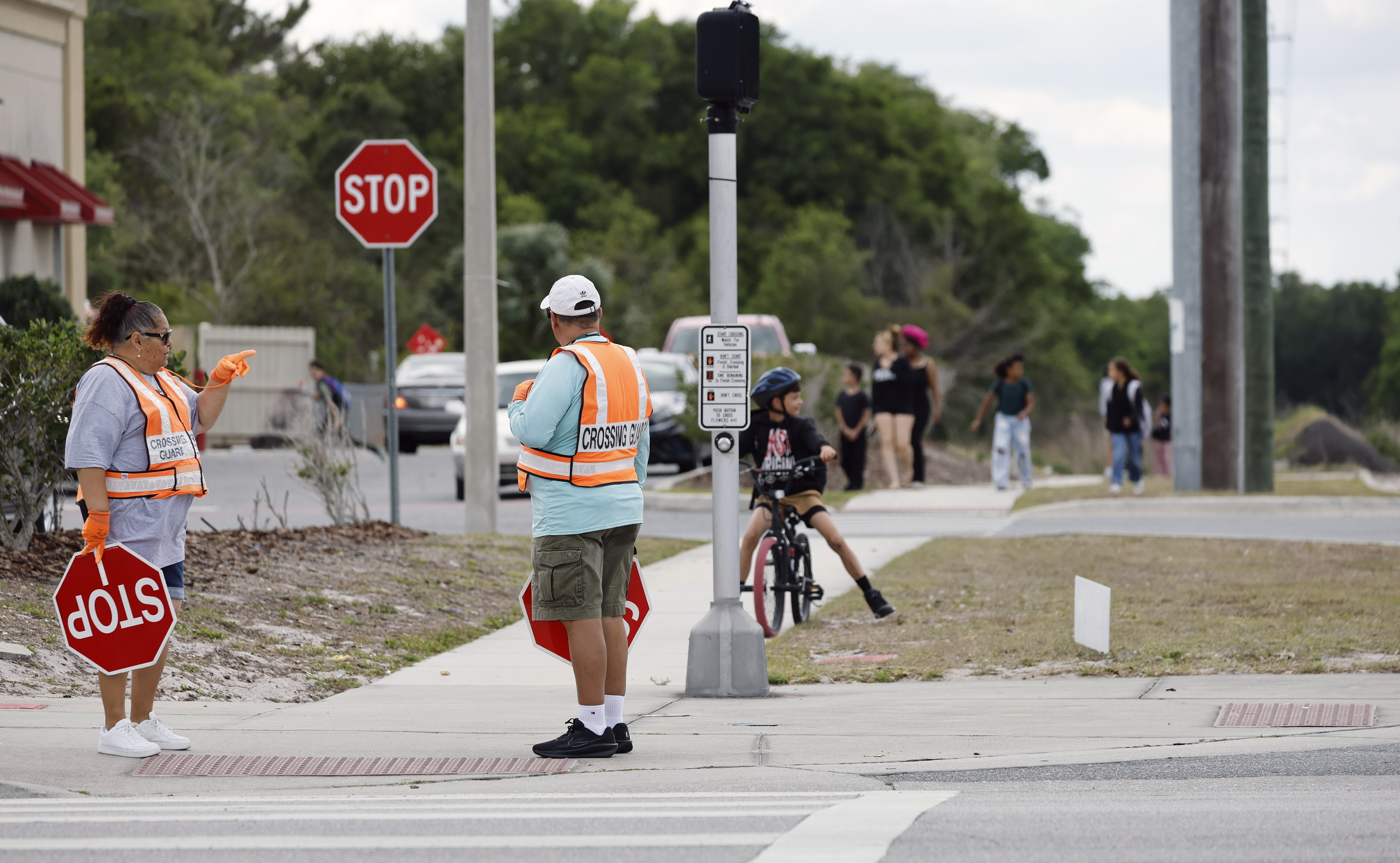 Los guardias de cruce esperan a que los peatones crucen la calle en Dean Road y Flowers Avenue durante la salida de la Escuela Primaria Union Park, el jueves 23 de abril de 2026. (Ricardo Ramirez Buxeda/Orlando Sentinel)