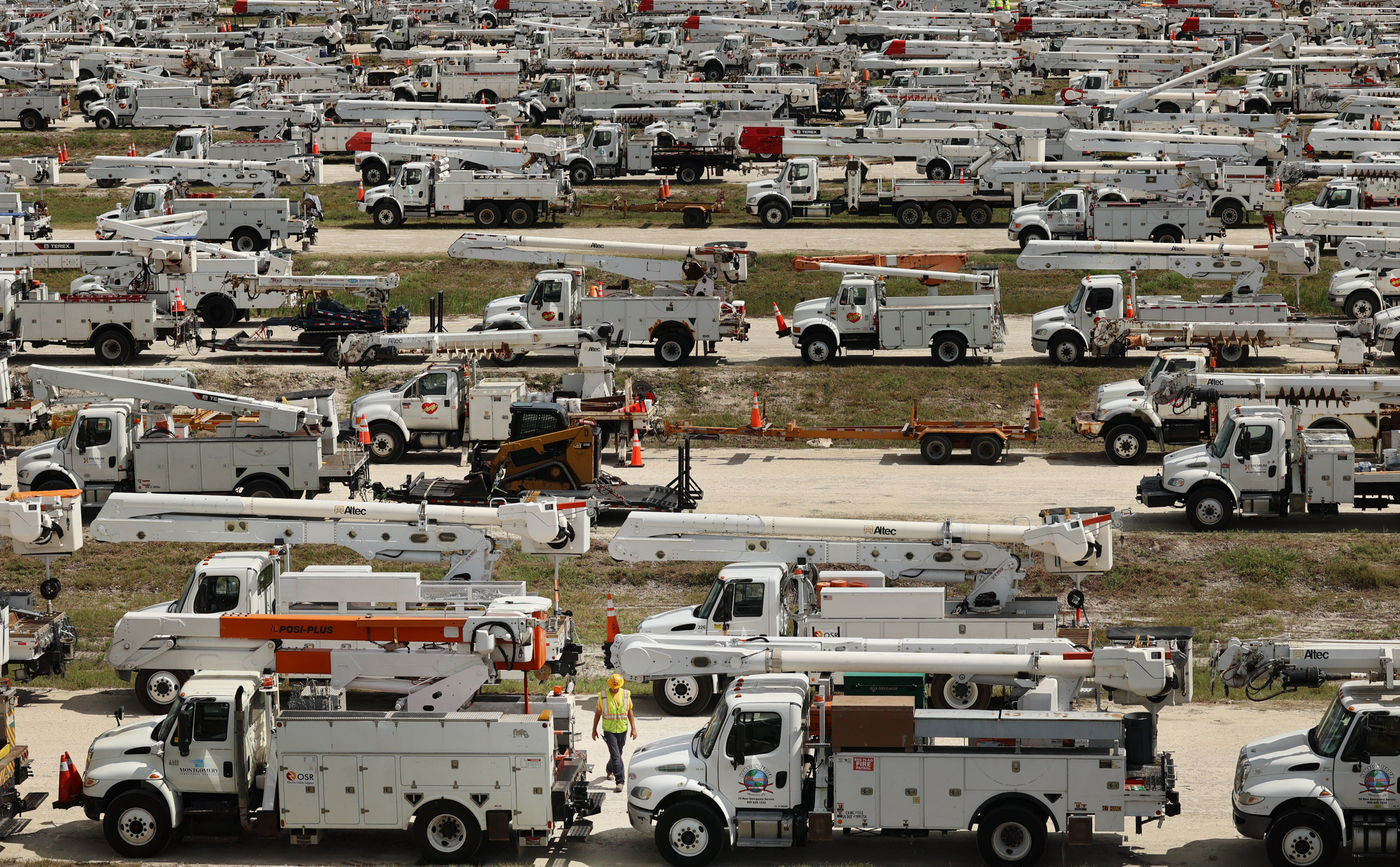El gerente de proyectos de Duke Energy, Tiger Yates (en el centro, en la parte inferior de la foto), camina entre los cientos de camiones de trabajadores colocados en The Villages el martes 8 de octubre de 2024. (Stephen M. Dowell/Orlando Sentinel)