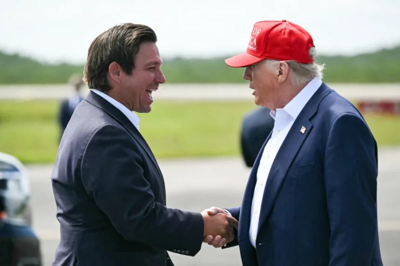 El gobernador de Florida, Ron DeSantis, estrecha la mano del presidente Donald Trump a la llegada de este al Aeropuerto de Entrenamiento y Transición Dade-Collier, en Ochopee, el 1 de julio de 2025.
