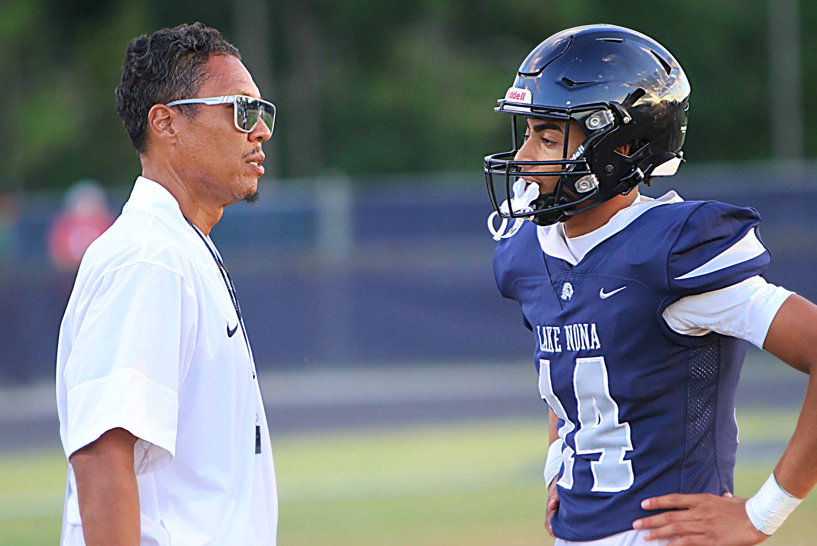 El entrenador de Lake Nona, David Aubrey, habla con su mariscal de campo suplente, Nick Lora, durante la victoria del jueves por la noche en el partido de primavera sobre Boone. (Chris Hays/Orlando Sentinel)